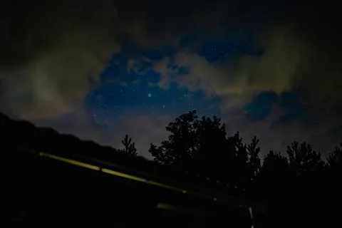 Starry Night Sky with Drifting Clouds and Tree Silhouettes Stock Photos