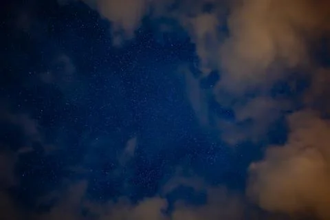 Starry Night Sky with Drifting Clouds and Golden Illumination Stock Photos