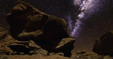 Starry night sky over large rock formations in remote desert location Ilustração Stock