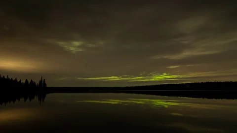 A starry night-sky time lapse with gray clouds moving above a calm lake.  Stock Footage 256243005