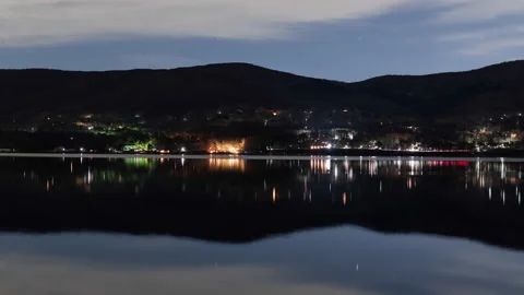 Starry Sky and Traffic Reflected in a Lake at Night (Time Lapse/Zoom Out) Stock Footage
