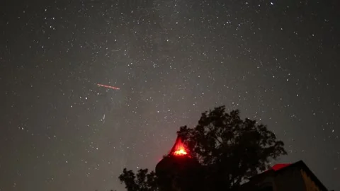 Starry sky timelapse above dark trees and old building with glowing red light Stock Footage 342444576
