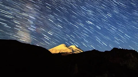 Stars draw lines and clouds over Mount Elbrus. Night landscape. Russia Stock Footage 84137176