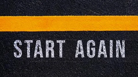 Start again text written and yellow line on the road in middle of the aspha.. Stock Photos