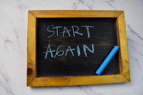 Start Again write on a chalkboard isolated on wooden table. 写真素材