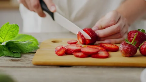 Start day with strawberries. Side view of woman's hand slicing fresh juicy s 動画素材 246533631