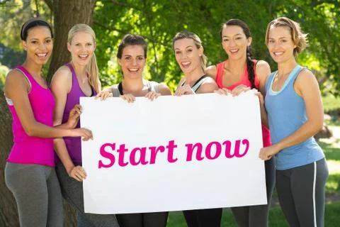 Start now against fitness group holding poster in park Stock Photos