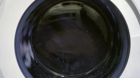 Start of a spin cycle in a laundry washing machine with clothing inside Stock Footage 196924804