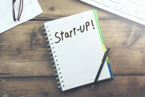 Start-up text on notebook and keyboard Stock Photos
