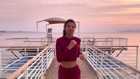 Start your morning. Front view of active young woman jogging along the beach on Stock Footage 151609361