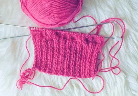 Started knitting with pink thread on a cozy sheepskin Stock Photos