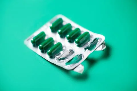 Started packing of tablets with green capsules. Green background. Probiotics, Stock Photos