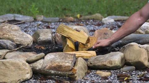 Starter fluid treated camp fire logs being lit by caucasian male with a green Stock Footage 342091851