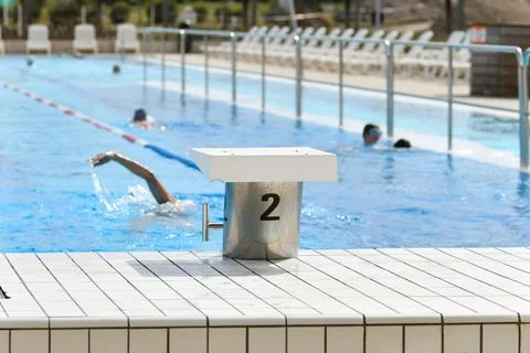 The starting blocks ready to jump into the pool and the swimmers are swimming 스톡 사진