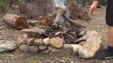 Starting camp fire using forest wood in fire pit made of large rocks Video stock 79180395