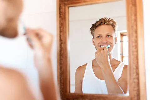 Starting the day on a minty fresh note. a young man brushing his teeth at home. Stock Photos