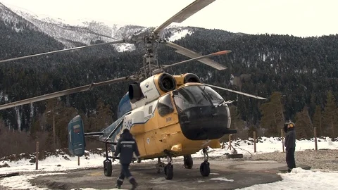 Starting engines Ka-32 helicopter on helipad against snow-capped mountains. Stock Footage 105777977