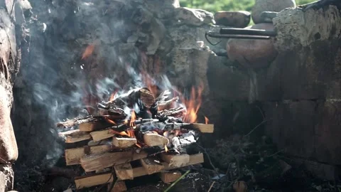 Starting a fire in a stone firepit outside on a sunny day, shot in 24FPS  Stock Footage 179022858