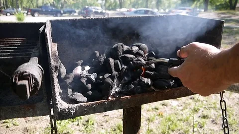 Starting a fire using charcoal on a park grill with a torch cooking on barbecue Stock Footage