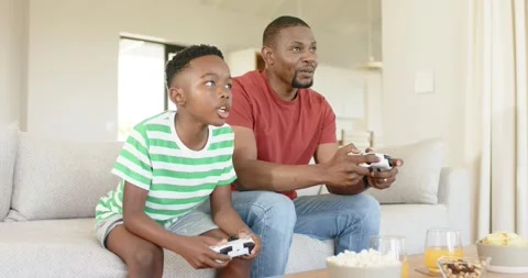 Starting game leading boy scooping popcorn while father pressing controller on Stock Footage 335454377