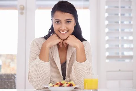 Starting her day with a hearty breakfast. A pretty young woman enjoying a fruit Stock Photos