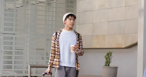Starting morning commute through urban walkway, Asian man pulling suitcase and Stock Footage 336242584