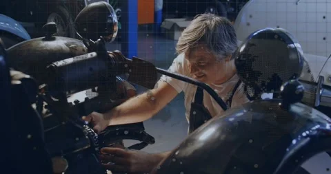 Starting with visual check, mature mechanic leaning into motorcycle and Stock Footage 329904388