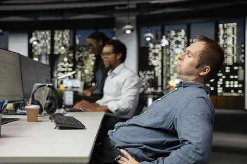 Startup engineer sits at office desk looking bored during slow workday Stock Photos
