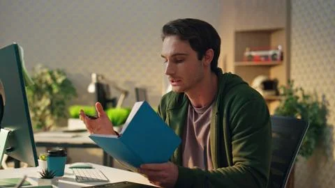 Startup guy reading notebook having video call office closeup. Man making notes Stock Photos