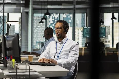 Startup helpdesk admin in office speaking in headset microphone Foto stock