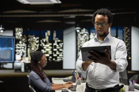 Startup manager looks at code on tablet written by employees 库存照片
