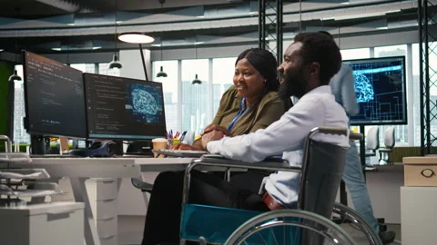 Startup office programmer in wheelchair talking with colleague, developing AI Stock Footage 313017925