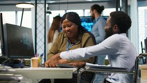 Startup office programmer in wheelchair talking with colleague, developing AI Foto stock