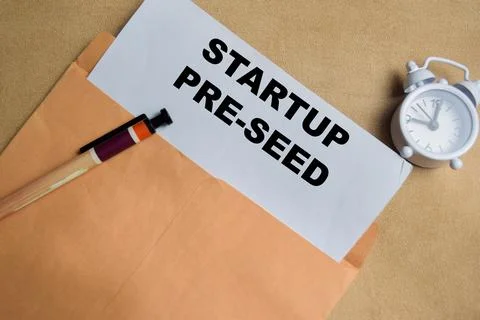 Startup pre-seed text on document above brown envelope. Stock Photos