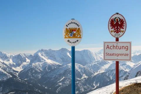 State German-Austrian border sgnboards on top Alpine mountain ridge Stock Photos