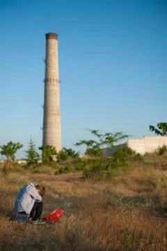 State of mind concept of small kid with head down near plant industrial facto Stock Photos