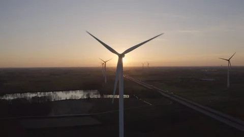 Static aerial drone shot of wind farm with 1 windmill blocking the sunset Stock Footage