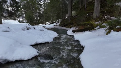 Static aerial of mountain stream with snowy banks, Lengau, Saalbach, 4K 60fps Vídeos de archivo 329922980