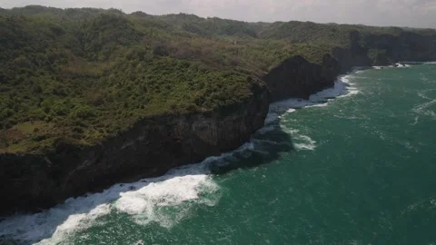 Static aerial shot of massive cliffs jutting down into the sea with big waves. Stock Footage 293714632