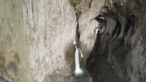 Static aerial shot of powerful mountain waterfall and massive basalt grotto Stock Footage 337023118