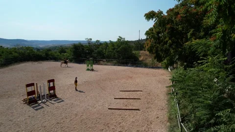 Static aerial of trainer in centre watching riders gallop around Stock Footage 315479989