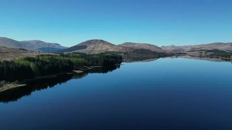 Static aerial view of reflective lake and hills in Scotland 動画素材 334459967