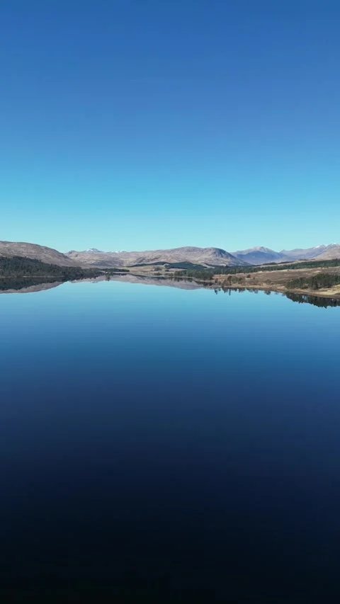 Static aerial view of reflective lake and hills in Scotland 動画素材 334459988