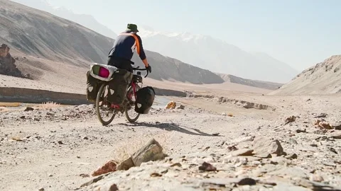 Static back view adventurous fit traveller cycle bicycle touring solo in re.. Stock-Footage 281638570