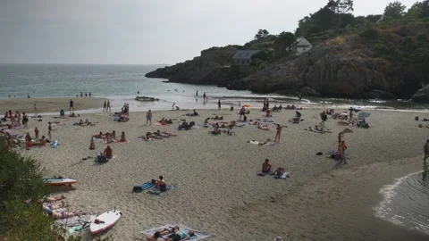 Static beach scene: overcast summer day, crowded sandy shore, rocky headland Stock Footage 341314280