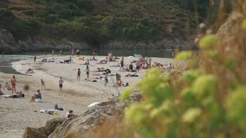 Static beach scene, summer daylight, crowded sandy cove surrounded by rocky Stock Footage 341314393