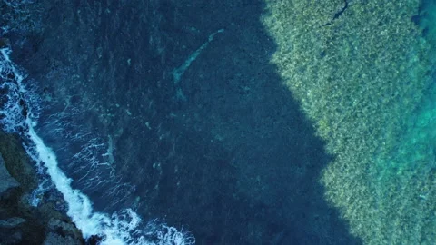 A static bird-eye view of waves crushing into the coast with turquoise water Stock Footage 232360163