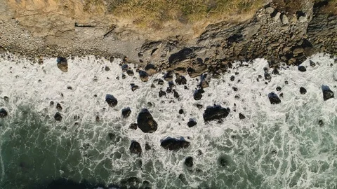 Static birds eye view of a rocky shoreline with waves crashing. Big boulders. 库存影片 87951769
