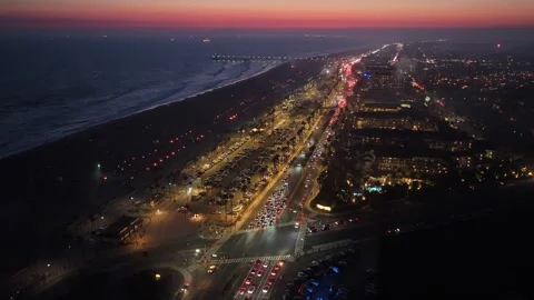 Static blue hour view of beach with pier, ocean waves, crimson horizon, urban Video stock 327392300