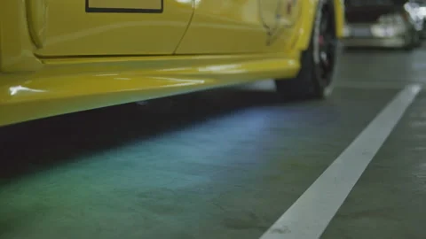Static cinematic shot of yellow car with underglow neon light on concrete flo Stock Footage 345654316